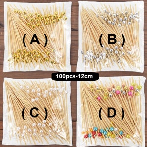 May include: Four bags of 100 bamboo skewers with decorative beads. The bags are labeled (A) through (D). Bag (A) has gold beads, bag (B) has silver beads, bag (C) has white beads, and bag (D) has multi-colored beads.