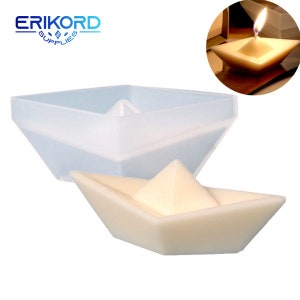 May include: A clear, geometric candle mould and a lit candle in a similar shape. The mould is a square-based pyramid shape with a central pyramid. The lit candle is ivory-coloured and has a small flame.