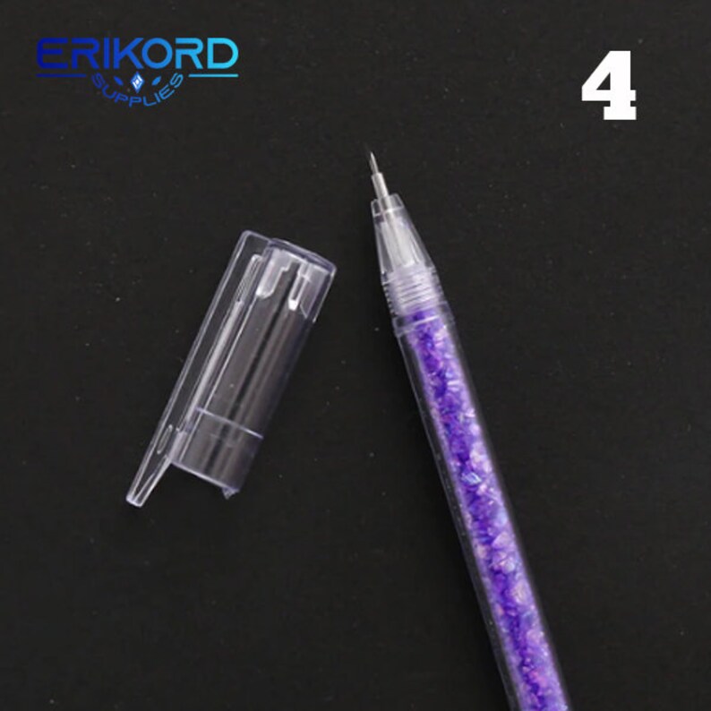 Puede incluir: Un bol&iacute;grafo de pl&aacute;stico transparente con un cuerpo de purpurina morada y un capuch&oacute;n de pl&aacute;stico transparente. El bol&iacute;grafo est&aacute; sobre una superficie negra. El n&uacute;mero "4" es visible en la esquina superior derecha de la imagen.