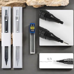 May include: A collection of mechanical pencils and lead refills. Two pencils are displayed in clear plastic cases, one black and one silver. A blue and white container of 0.3mm HB lead is also shown. Two black pencils are on white squares, and one is drawing a line.