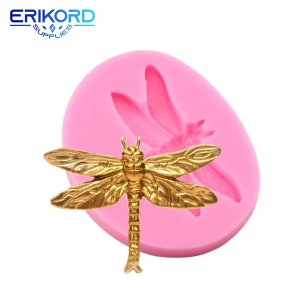 May include: A golden dragonfly mold with a pink silicone base. The dragonfly is detailed with textured wings and body. The image also shows the "ERIKORD SUPPLIES" logo in blue.