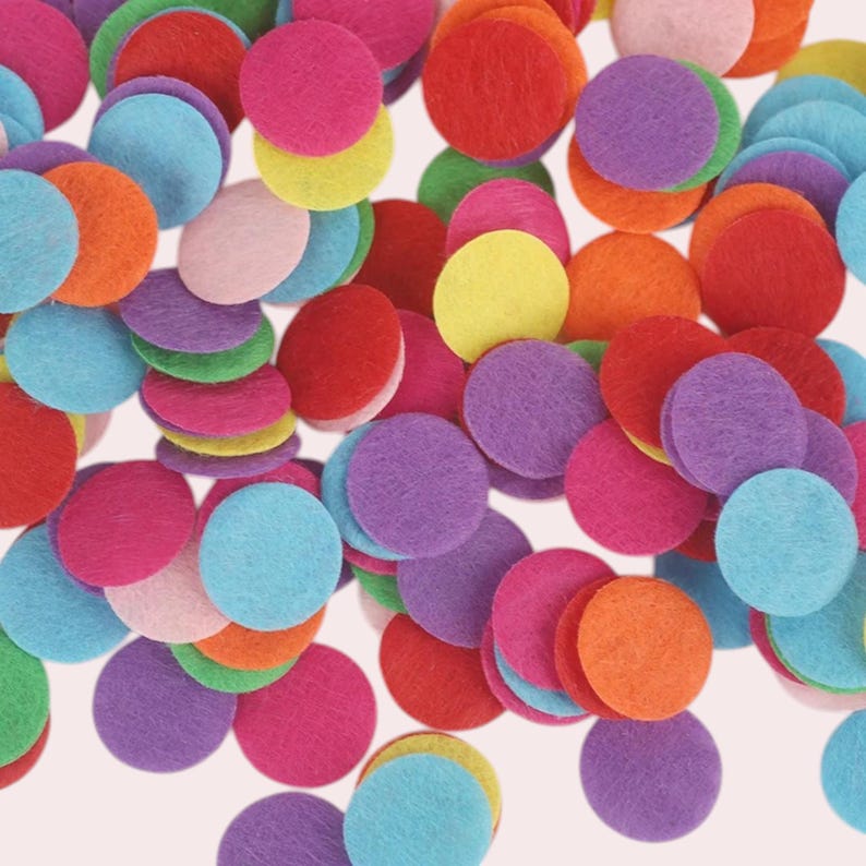Op de afbeelding: Een verzameling kleurrijke viltcirkel in verschillende tinten rood, roze, oranje, geel, groen, blauw en paars. De cirkels zijn verspreid over een witte achtergrond.