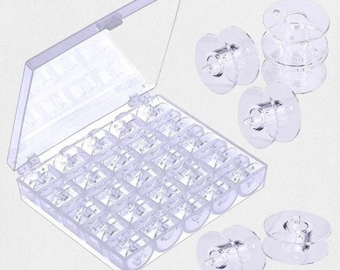 May include: A clear plastic sewing bobbin storage box with an open lid, filled with clear bobbins. Several loose bobbins are scattered around the box. The bobbins are made of clear plastic.