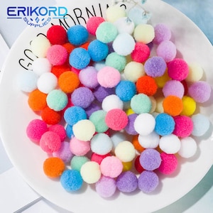 Puede incluir: Una colección de pompones coloridos en varios tonos de rojo, naranja, amarillo, verde, azul, morado, rosa y blanco. Los pompones están esparcidos sobre un plato blanco. La imagen incluye el texto "ERIKORD SUPPLIES".