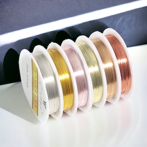 May include: Spools of jewelry wire in various metallic colors, including silver, gold, rose gold, and copper. The wire is 0.3 mm in diameter. The spools are arranged in a row, showcasing the different color options available for jewelry making.