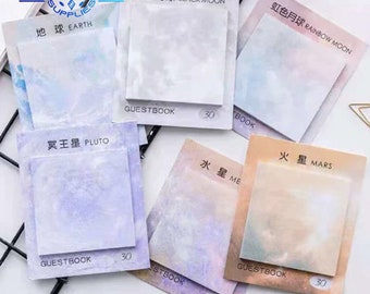 May include: A set of 6 colourful sticky note pads with a galaxy theme. Each pad has a different colour and a different planet name in English and Chinese. The pads are labelled "GUESTBOOK" and have 30 sheets each.