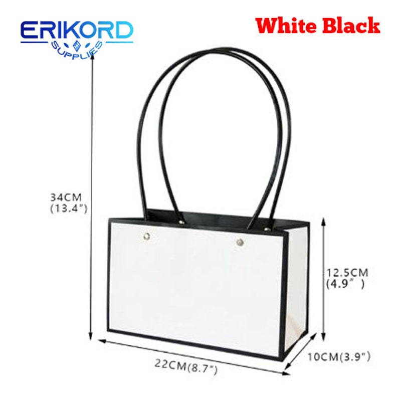 Puede incluir: Bolsa de regalo blanca con asas y ribetes negros. La bolsa mide 34 cm de alto, 22 cm de ancho y 12,5 cm de profundidad.