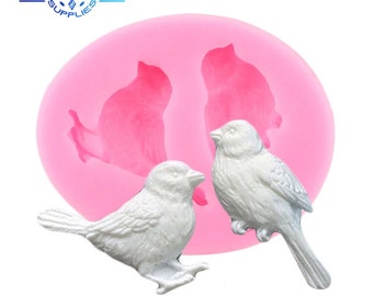 May include: Pink silicone mold with two bird shapes. The mold is designed to create two small bird-shaped decorations.