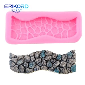 Puede incluir: Molde de silicona rosa para hacer un diseño de camino de piedra ondulado. El molde está vacío y muestra el diseño detallado del camino. Se muestra una muestra del camino terminado debajo del molde.