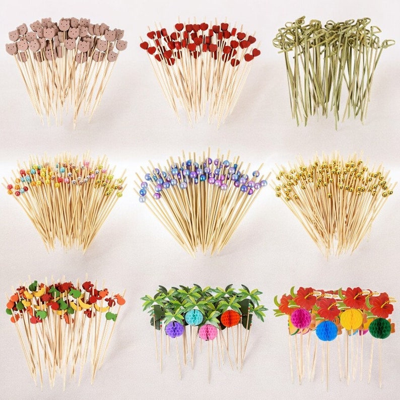 May include: Assortment of colorful wooden cocktail sticks with various decorative toppers, including hearts, animals, beads, and tropical themes.