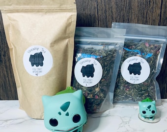 May include: Three bags of loose leaf tea with labels that say "Vinewhip Tea" and "Fox Craft Apothecary". The bags are on a wooden surface with two green cartoon figures in front of them.