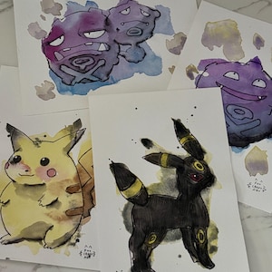 May include: Watercolor paintings of Pokémon characters, including Pikachu, Umbreon, and Koffing. The artwork features vibrant colors and detailed illustrations on individual cards. The style is whimsical and artistic, with a hand-painted aesthetic.