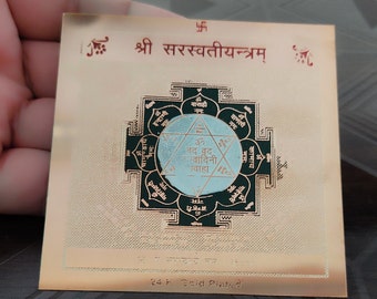 Puede incluir: Una placa chapada en oro con un diseño de mandala verde y blanco. La placa presenta el texto "श्री सरस्वतीयन्त्रम्" y "24 K Gold Plated".