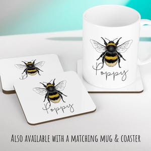 May include: White ceramic mug with a black and yellow bumblebee illustration and the word "Poppy" written in black script. Two white ceramic coasters with the same bumblebee illustration and the word "Poppy" written in black script.
