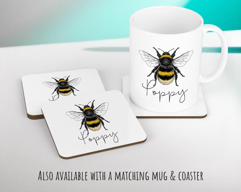 May include: White ceramic mug with a black and yellow bumblebee illustration and the word "Poppy" written in black script. Two white ceramic coasters with the same bumblebee illustration and the word "Poppy" written in black script.
