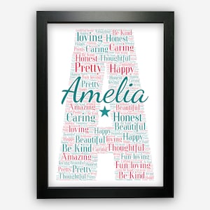 May include: A framed print featuring a word cloud in the shape of the letter "A" and the name "Amelia". The word cloud is composed of positive words such as "caring", "happy", "loving", "honest", and "beautiful" in shades of pink and teal.