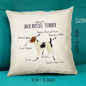 May include: A white and beige pillow with a Jack Russel Terrier illustration and the text "Anatomy of a Jack Russel Terrier". The illustration shows the dog's body parts labeled with humorous names like "Blinkers", "Snack Detector", "Selective Hearing Device", "Happiness Meter", "Rub Here", "Toesies", and "Used to Chase Cats". The pillow is 16 inches by 16 inches.