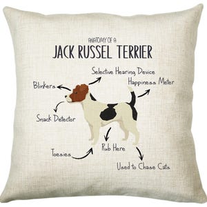 May include: A beige throw pillow with a white Jack Russel Terrier illustration and the text "Anatomy of a Jack Russel Terrier". The illustration shows the dog's body parts labeled with humorous names like "Blinkers", "Snack Detector", "Happiness Meter", "Toesies", and "Used to Chase Cats".