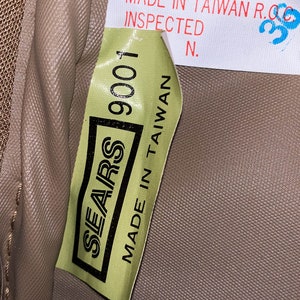 May include: A green label with the text "SEARS 9001 MADE IN TAIWAN" on a brown fabric background. The label also has the text "MADE IN TAIWAN R.O.C. INSPECTED N."