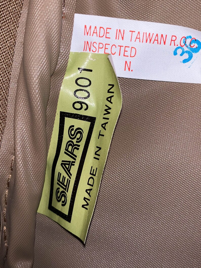 May include: A green label with the text "SEARS 9001 MADE IN TAIWAN" on a brown fabric background. The label also has the text "MADE IN TAIWAN R.O.C. INSPECTED N."