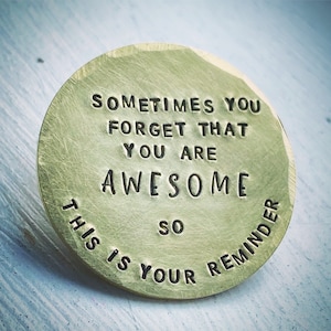 May include: A circular, brass-toned metal coin with the stamped message: "SOMETIMES YOU FORGET THAT YOU ARE AWESOME SO THIS IS YOUR REMINDER". The coin has a textured surface and a vintage look, perfect as a small gift or keepsake.