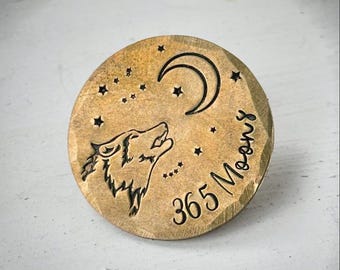 Op de afbeelding: Een ronde, bronskleurige hanger met een huilende wolf, een halve maan en sterren. De tekst "365 Moons" is rond de rand gegraveerd. De hanger heeft een rustieke, getextureerde uitstraling.