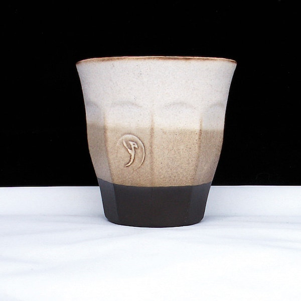 May include: A white, brown, and black ceramic mug with a geometric design and a stylized bird logo.