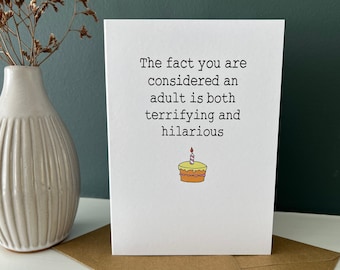 May include: A white card with the text "The fact you are considered an adult is both terrifying and hilarious" and a simple line drawing of a yellow birthday cake with a single lit candle.
