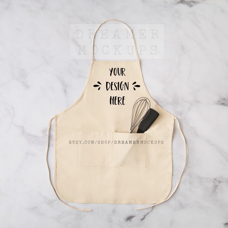 May include: A plain white apron with a large pocket on the front. The pocket has a whisk and a spatula inside. The apron has the text "YOUR DESIGN HERE" printed on the front.