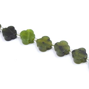 Könnte beinhalten: Nahaufnahme einer Kette aus grünen Jade-Kleeblatt-Perlen. Die Perlen sind auf einem silberfarbenen Draht aufgereiht. Der Jade weist Farbvariationen auf, die von Dunkelgrün bis Hellgrün reichen.