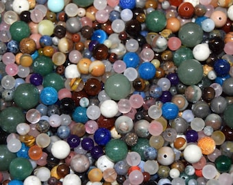 Pode incluir: Um grande sortimento de contas de pedras preciosas coloridas, incluindo verde, azul, rosa, marrom e branco. As contas são de vários tamanhos e formas, perfeitas para a fabricação de joias.