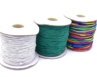 May include: Three spools of elastic cord, one white, one teal green, and one with a rainbow of colors.