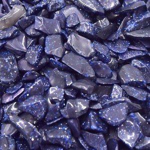Peut inclure: Gros plan sur un tas de copeaux de pierre de soleil bleue. Les copeaux sont de forme irrégulière et ont une finition brillante et scintillante.