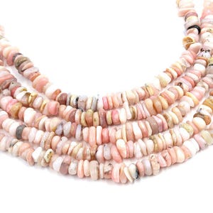Peut inclure: Un brin de perles de pierres précieuses d'opale rose, présentant un mélange de nuances de rose clair et foncé. Les perles sont de forme irrégulière et ont une finition naturelle et polie.