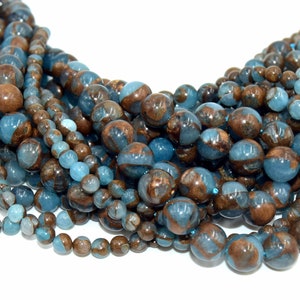 Peut inclure: Un brin de perles de pierres précieuses bleues et brunes. Les perles sont rondes et ont un aspect marbré.