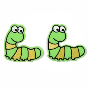 Peut inclure: Deux écussons brodés représentant un ver de dessin animé. Les vers sont principalement vert clair avec des segments rayés jaunes et noirs. Chaque ver a de grands yeux blancs bordés de noir et une bouche souriante. Les écussons sont sur fond blanc.