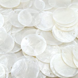 Può includere: Una collezione di perline rotonde bianche in madreperla. Ogni perlina ha un piccolo foro per l'infilatura. Le perline hanno una lucentezza perlacea e sono ideali per la creazione di gioielli o progetti artigianali.