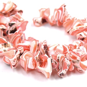 Può includere: Una collana di perle di conchiglia rosa e bianca, ogni perla ha una forma unica e irregolare.