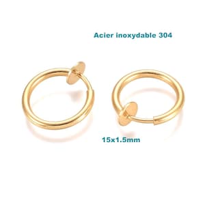 Peut inclure: Deux boucles d'oreilles créoles dorées avec fermoir à charnière. Les boucles d'oreilles mesurent 1,5 cm de diamètre et 1,5 mm d'épaisseur. Le texte "Acier inoxydable 304" est au-dessus.