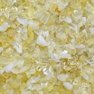 Peut inclure: Gros plan sur un tas de petites pierres jaunes et blanches translucides. Les pierres sont lisses et polies, et ont un aspect naturel et terreux.