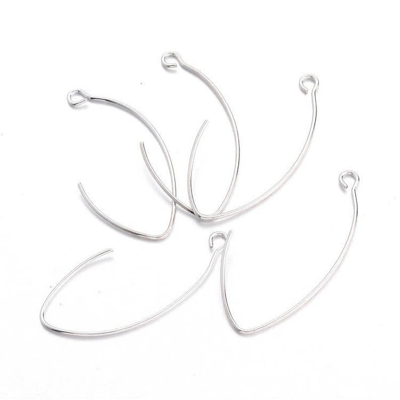 May include: Five silver jump rings, each with a circular shape and a small opening at the top. The rings are arranged in a loose pile.