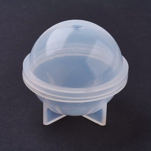 Peut inclure: Un moule en plastique transparent pour la fabrication d'objets ronds et sphériques. Le moule a un dessus amovible et une base à trois pieds.
