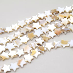 Peut inclure: Un brin de perles en forme d'étoile en coquillage blanc et crème. Les perles sont disposées en forme de vague.