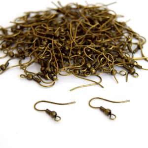 May include: A large pile of gold-toned earring hooks. The hooks are made of metal and have a small loop at the top. There are two individual hooks in the foreground.