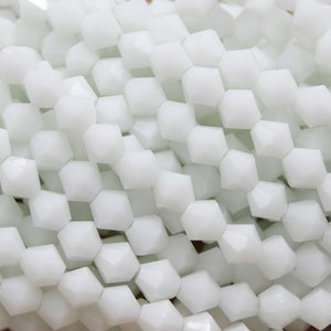 May include: White faceted glass beads, perfect for jewelry making or crafting projects.