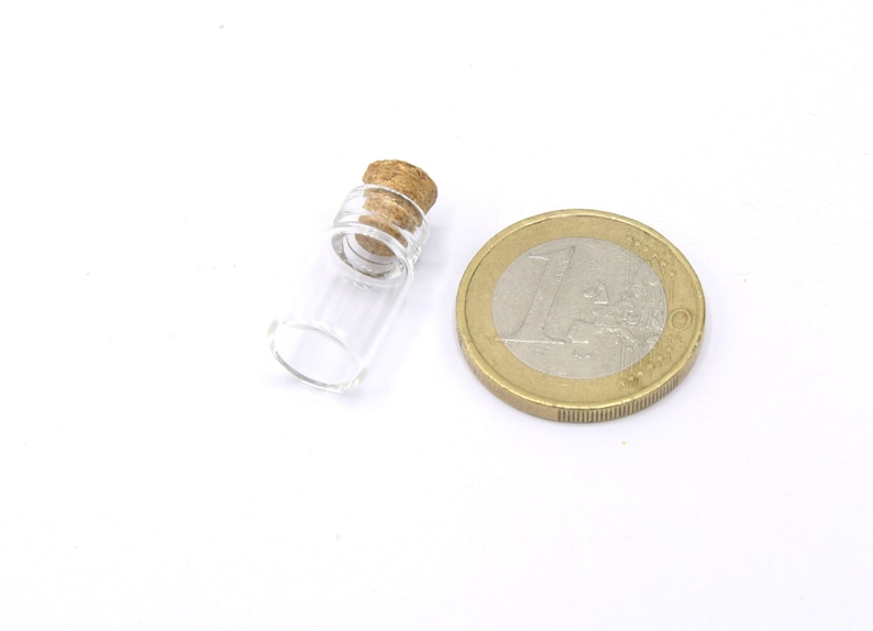 May include: A small, clear glass bottle with a cork stopper. The bottle is about the size of a US one-euro coin.