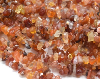 May include: A strand of carnelian chip beads in various shades of orange, red, and brown. The chips are irregular in shape and size, creating a natural and earthy look.