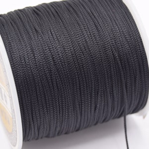 Peut inclure: Une bobine de cordon ciré noir, un type de ficelle utilisé pour l'artisanat et la fabrication de bijoux.