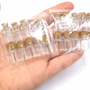 May include: Two packages of small, clear glass bottles with cork stoppers. The bottles are arranged in rows and are packaged in clear plastic.