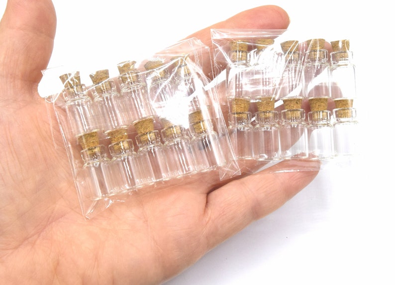 May include: Two packages of small, clear glass bottles with cork stoppers. The bottles are arranged in rows and are packaged in clear plastic.